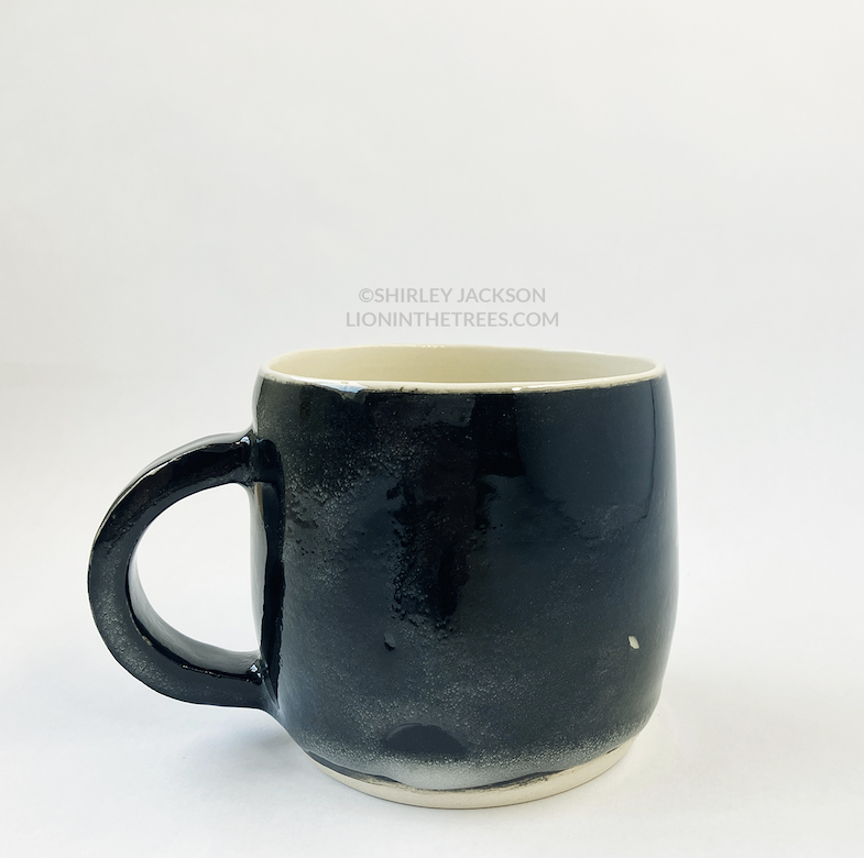 Photo of the back of my black sgraffito running horse mug. This shot demonstrates the clear glaze error.