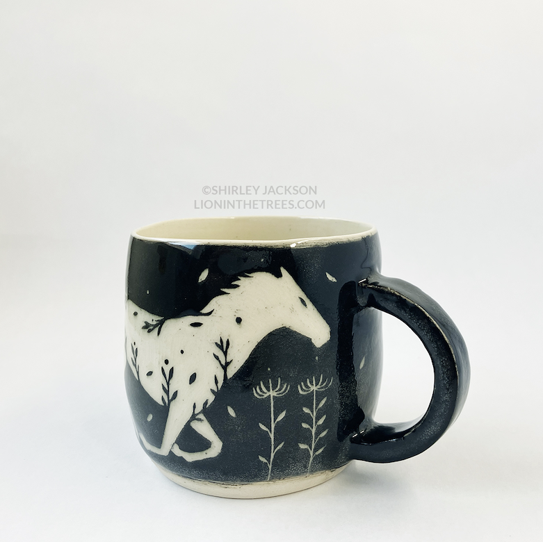Photo of my black sgraffito mug that features my running horse motif.