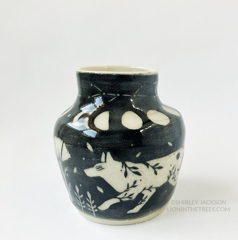 Photo of my black sgraffito vase featuring my running wolf motif, poppies, and moon cycles