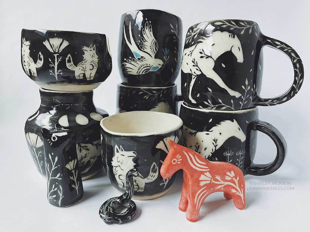 Group photo of my latest pottery. Features a variety of bowls and mugs with black sgraffito designs consisting of my running horse, keeper wolves, and new swallow motif. There is also a bear totem, a small snake totem, and red horse totem.