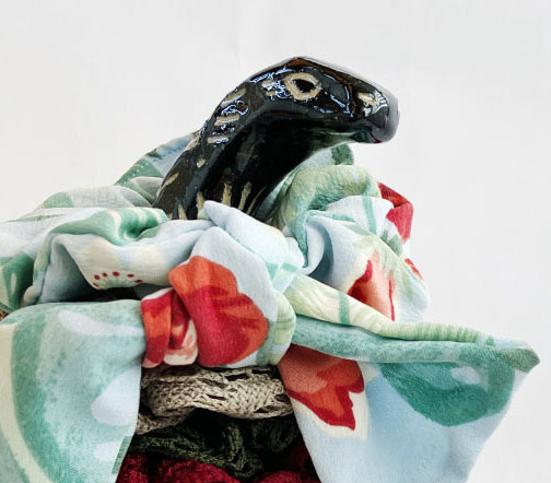 Cropped image of the Brontosaur sculpture from the neck up with scrunchies on it's neck.