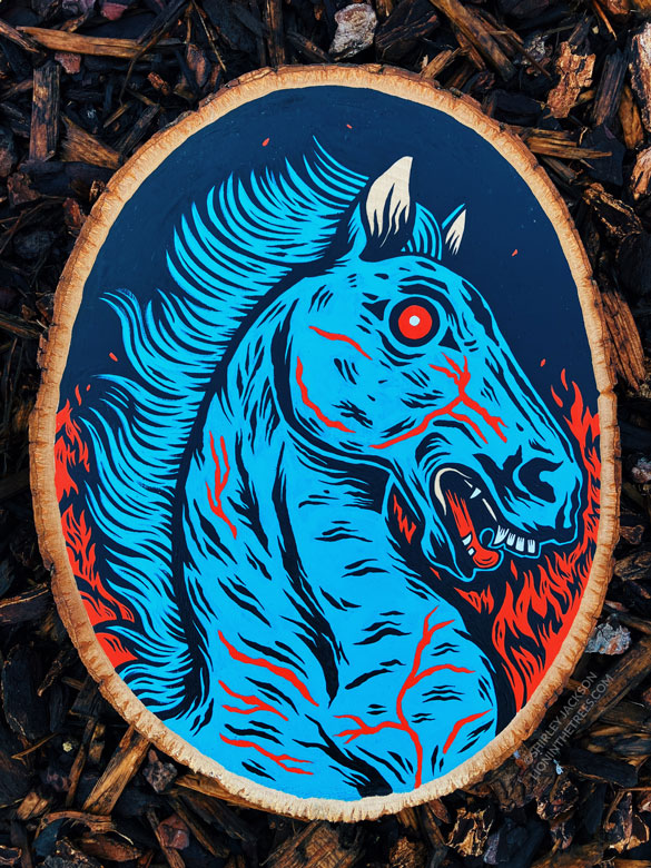 A painting on a wood slice featuring the infamous Denver Blue Mustang lovingly nicknamed "Blucifer" with the flames of Hell.