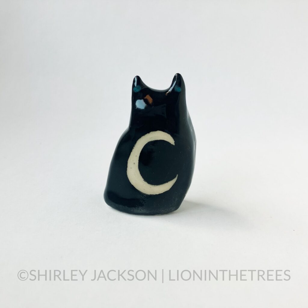 A ceramic sgraffito Horned Owl Totem with black underglaze, and a crescent moon on it's back.