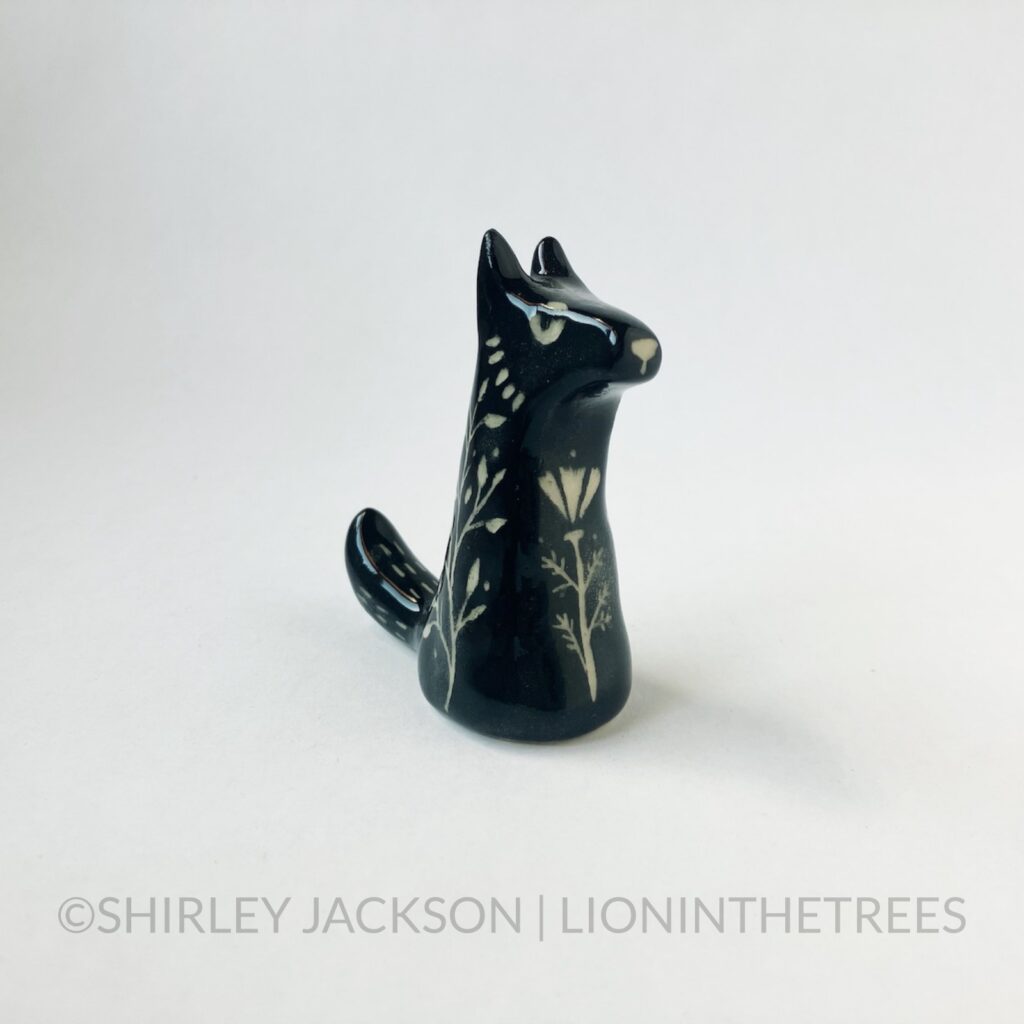 Right Side View - Small ceramic sgraffito wolf totem done with black underglaze and features a California Poppy on it's torso.