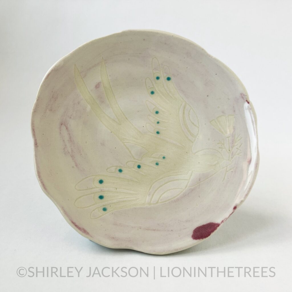 Front View - Ceramic sgraffito trinket dish with a light pink/magenta underglaze featuring my Barn Swallow motif. I didn't apply the magenta glaze properly so the colour looks wrong LMAOOO