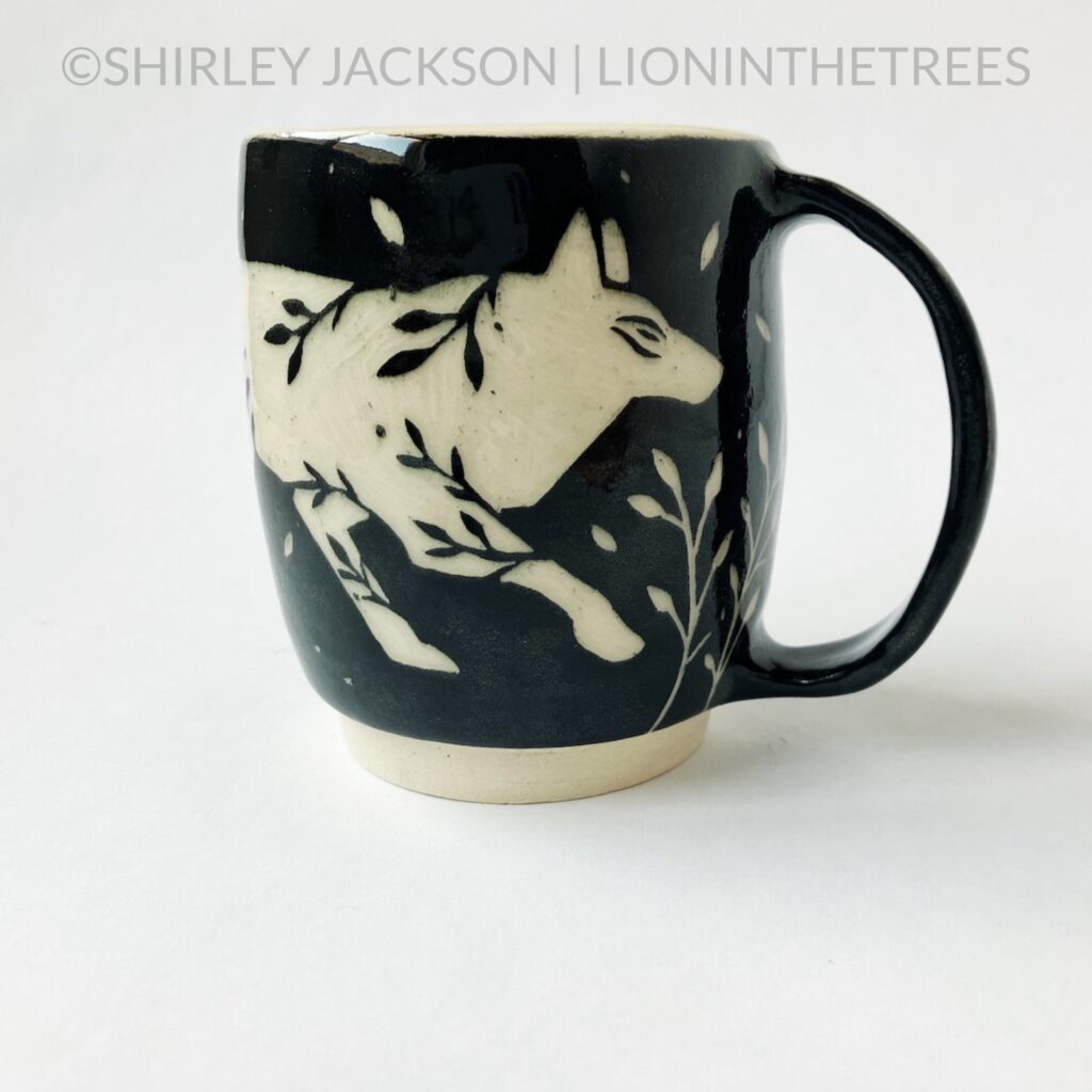 Front View - Ceramic sgraffito mug with black underglaze featuring my running floral wolf motif.