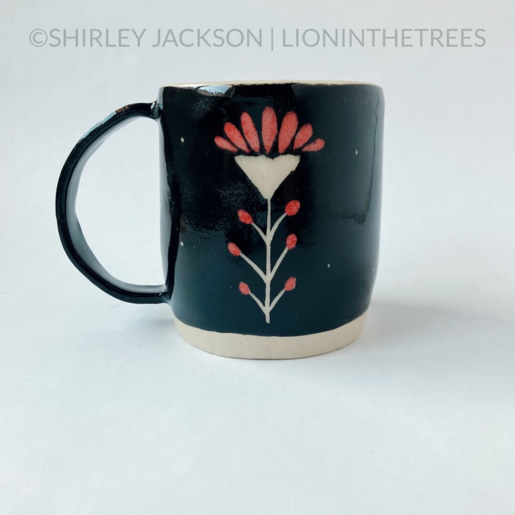 Back View - Ceramic sgraffito mug featuring a Prairie Fire flower motif on the back.