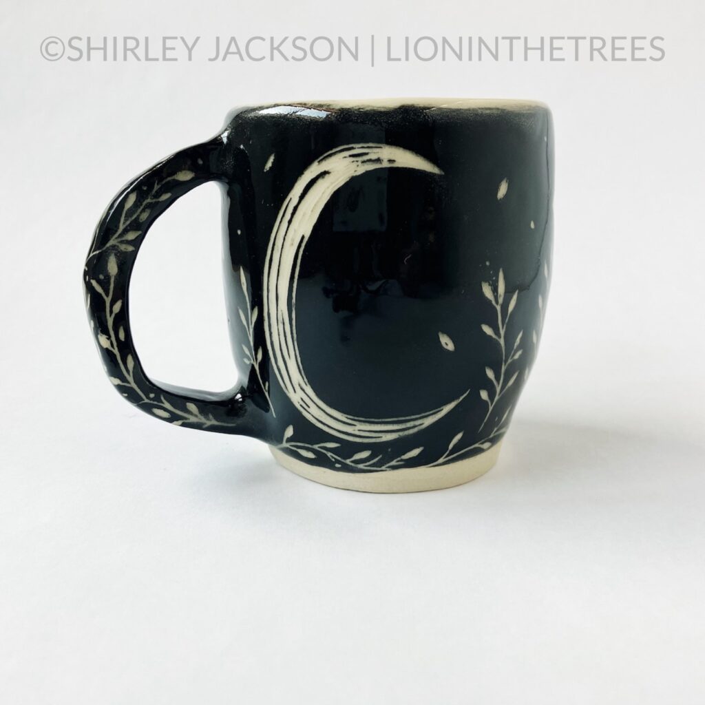 Back View - Ceramic sgraffito mug with black underglaze featuring my running floral wolf motif and a crescent moon on the back.