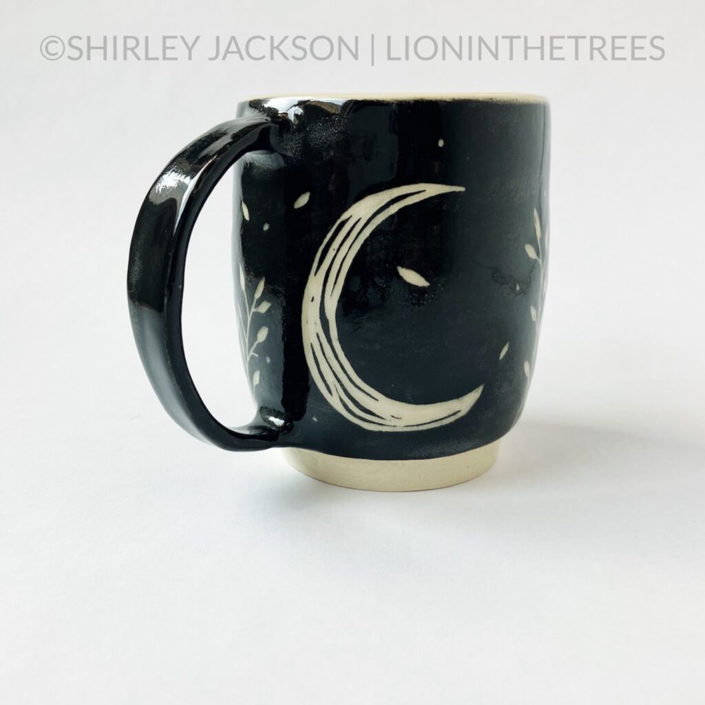 Back View - Ceramic sgraffito mug with black underglaze featuring my running floral wolf motif and a crescent moon detail on the back.