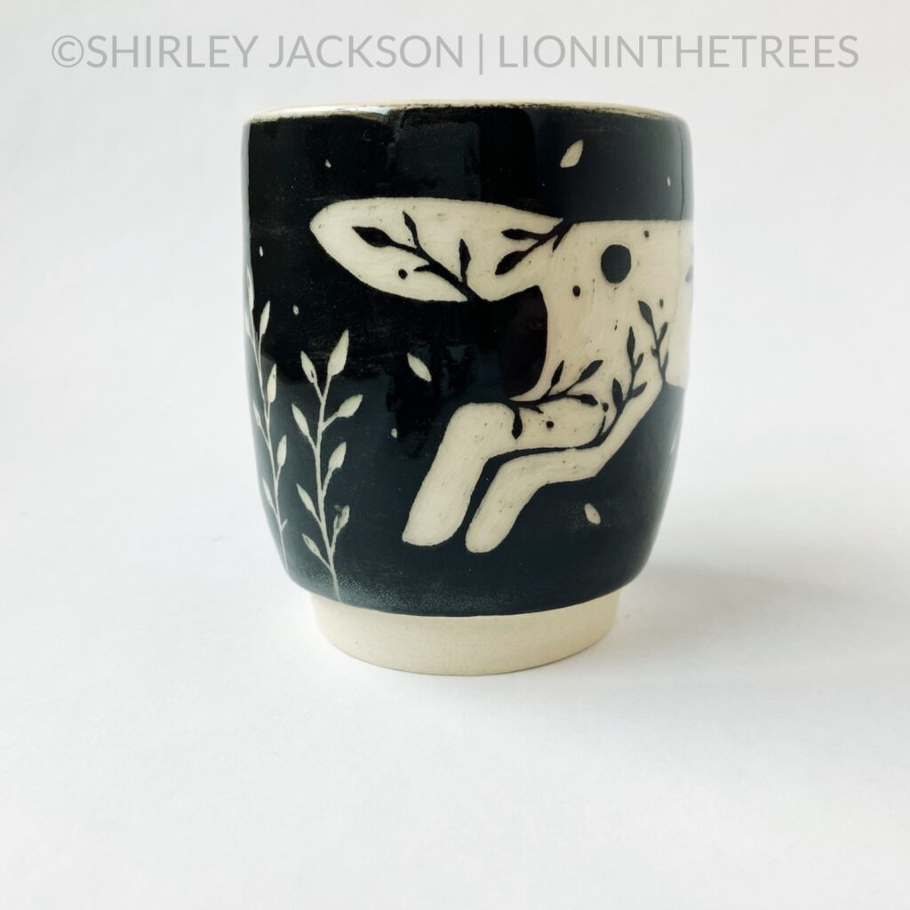 Side View - Ceramic sgraffito mug with black underglaze featuring my running floral wolf motif.