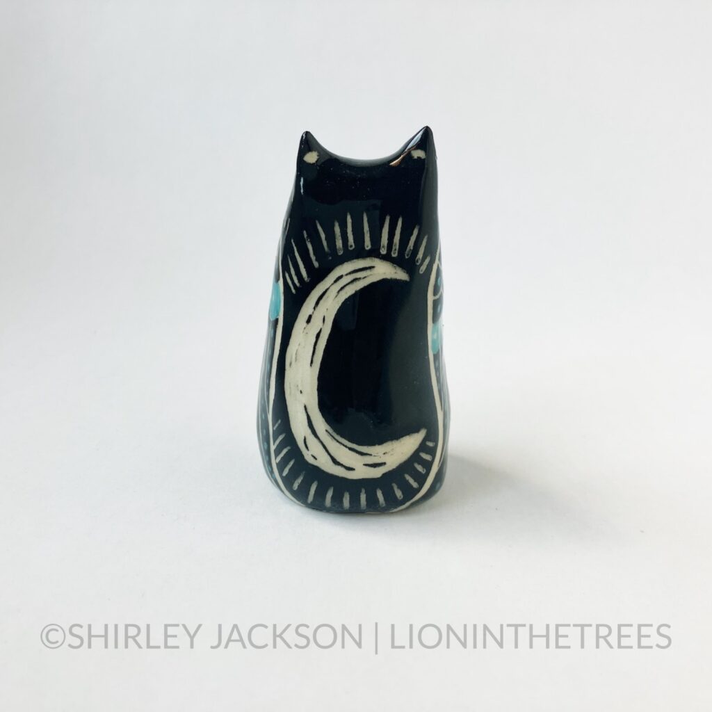 A ceramic sgraffito Horned Owl Totem with black and turquoise underglaze, and a crescent moon on it's back.