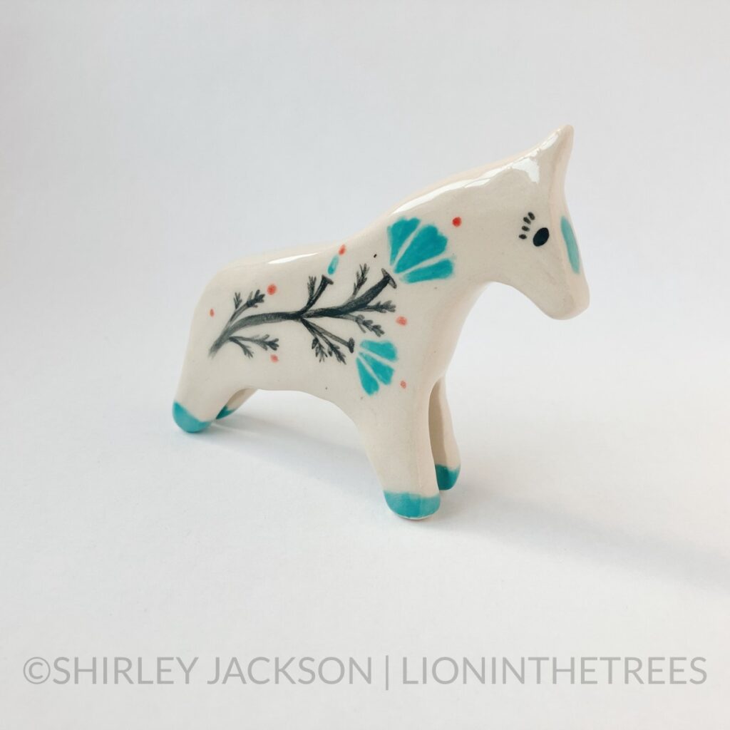 Right Side View - Ceramic sgraffito horse totem done with turquoise, black, and red underglaze and a California Poppy along it's side.