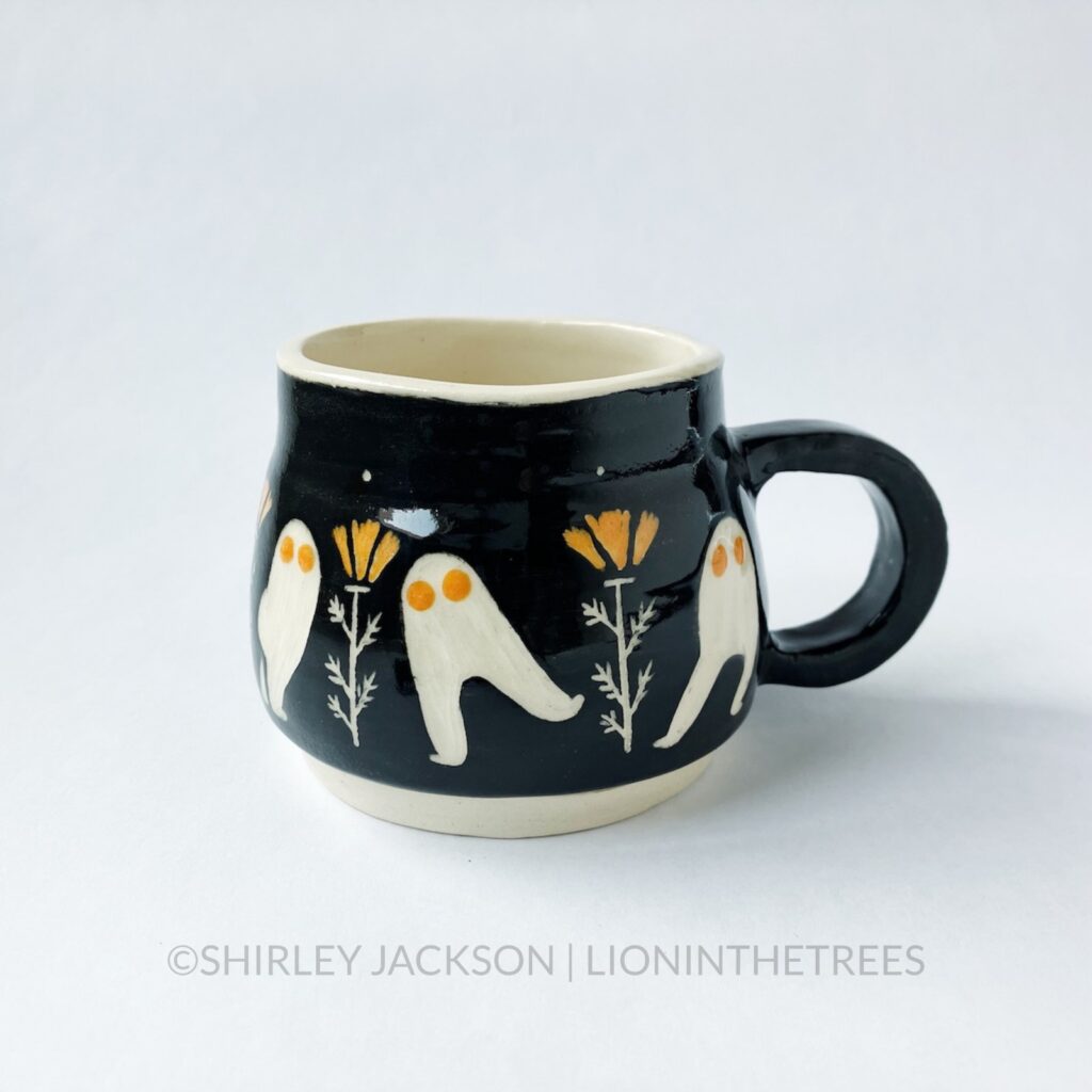 Ceramic black sgraffito mug with bright orange details featuring my Dance of the Fresno Nightcrawler motif and California Poppies.