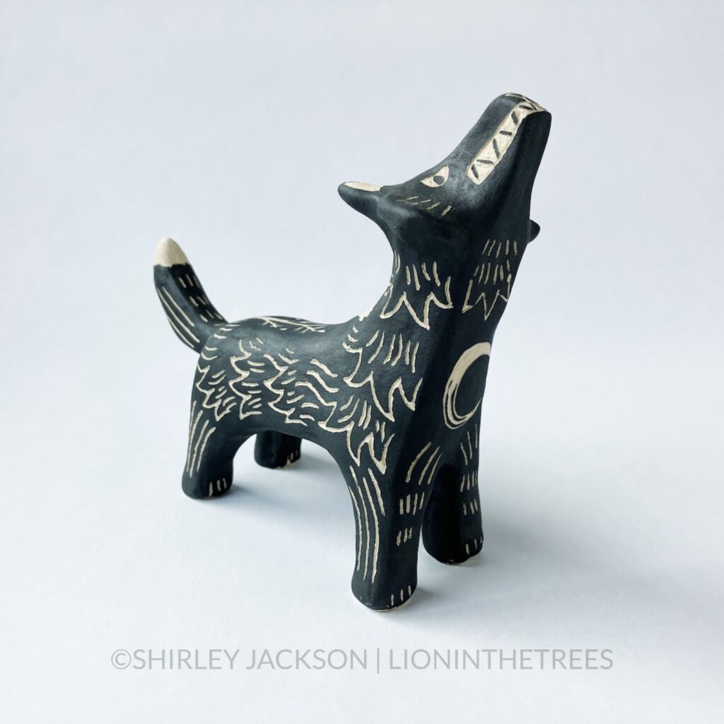 Ceramic black sgraffito howling wolf totem with a crescent moon motif on it's chest.