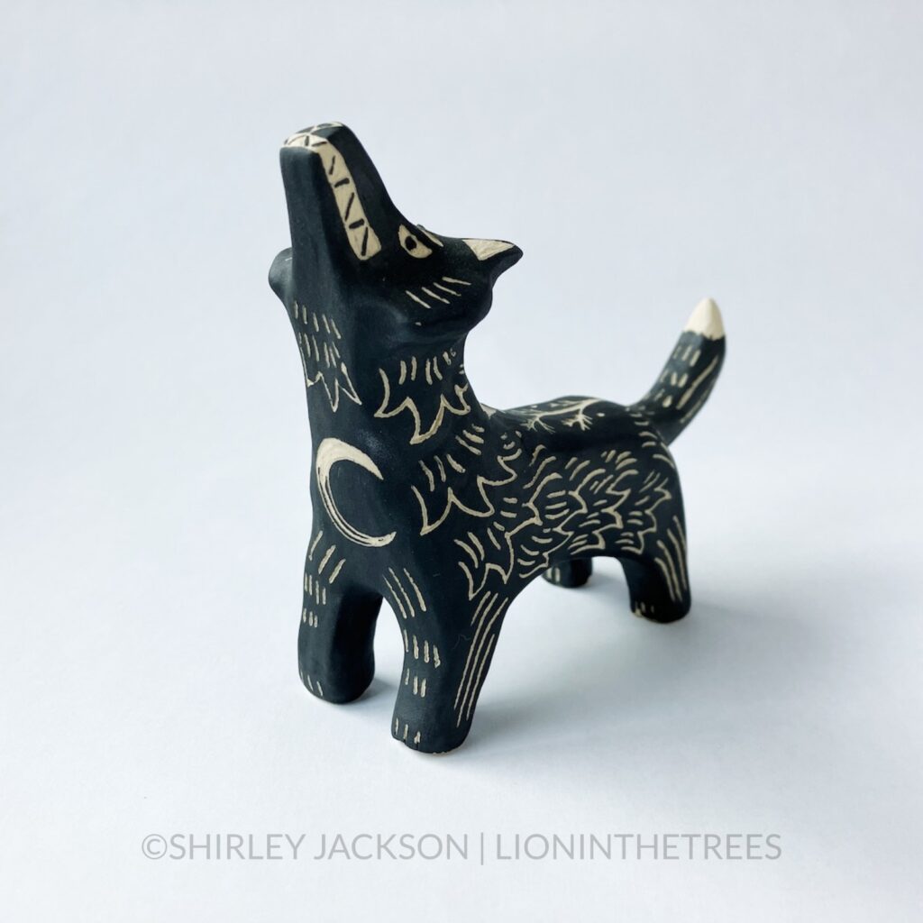 Ceramic black sgraffito howling wolf totem with a crescent moon motif on it's chest.