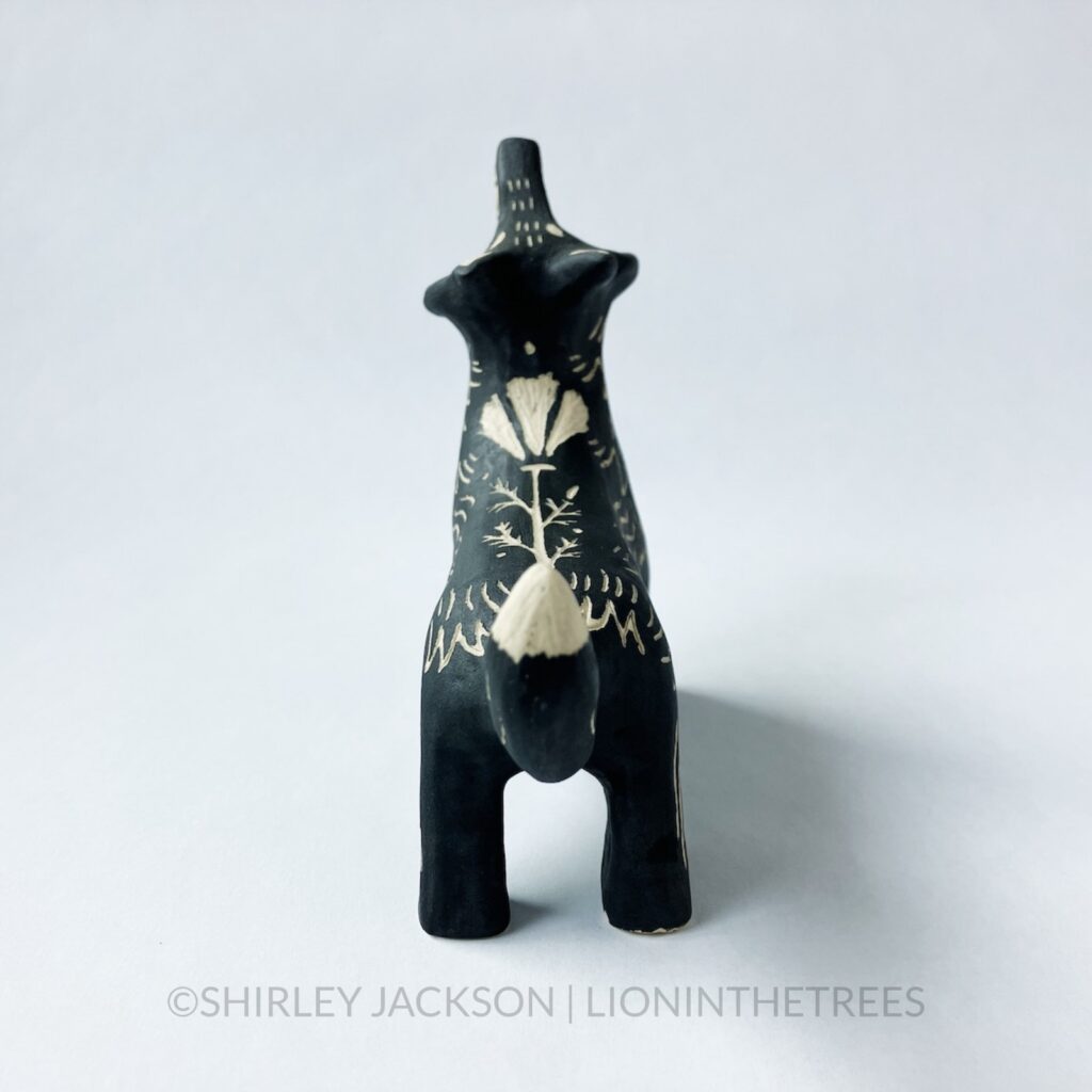 Ceramic black sgraffito howling wolf totem with a crescent moon motif on it's chest and a California Poppy on it's back