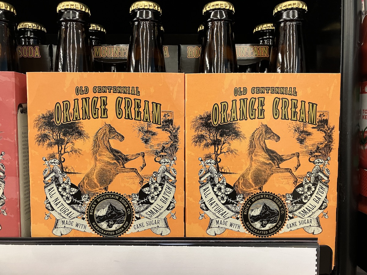 Rocky Mountain Soda Co.'s Old Centennial Orange Cream pop that shows a vintage styled illustration of a rearing horse done in black against an orange background.