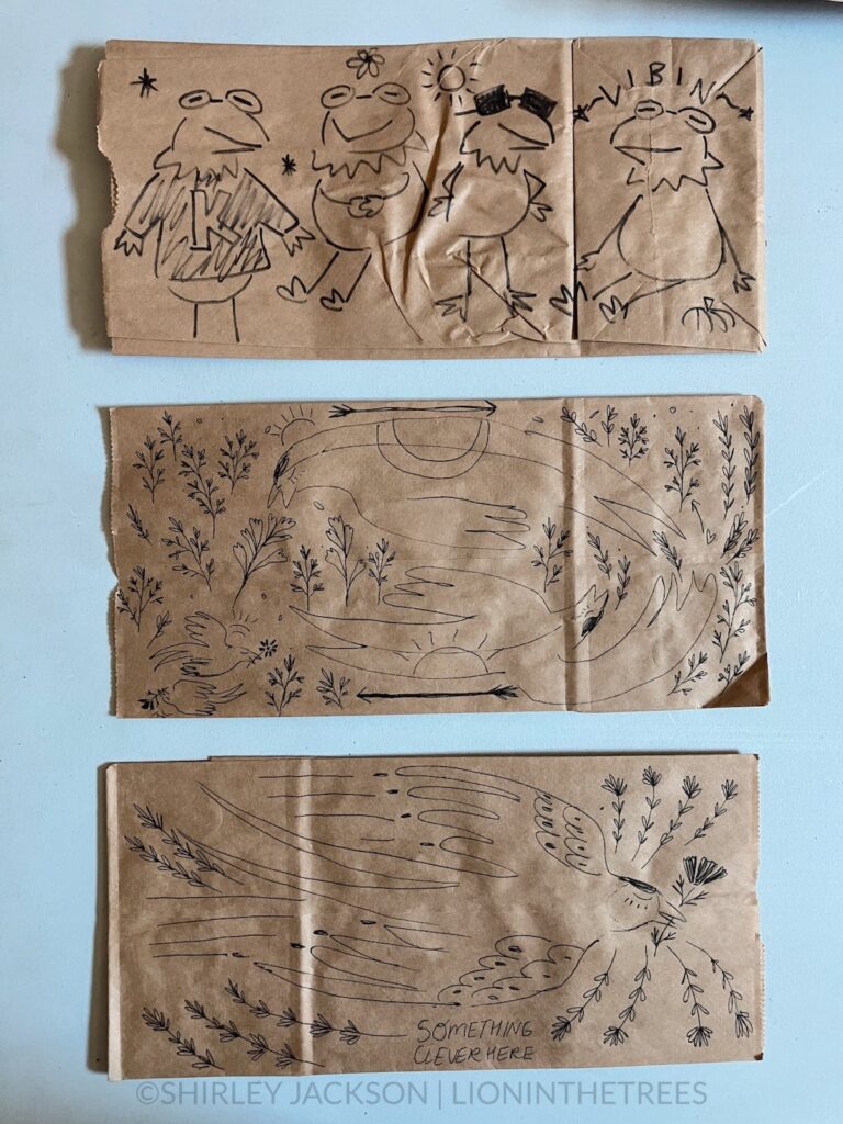 A photo of 3 brown paper lunch bags with a variety of doodles drawn with a sharpie and pen on them. This variety features subject matter such as Kermit the Frog and Barn Swallows.