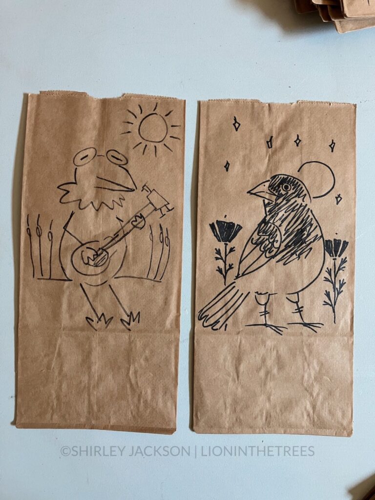 A photo of 2 brown paper lunch bags with a variety of doodles drawn with a sharpie on them. These bags feature Kermit the Frog and a House Sparrow.