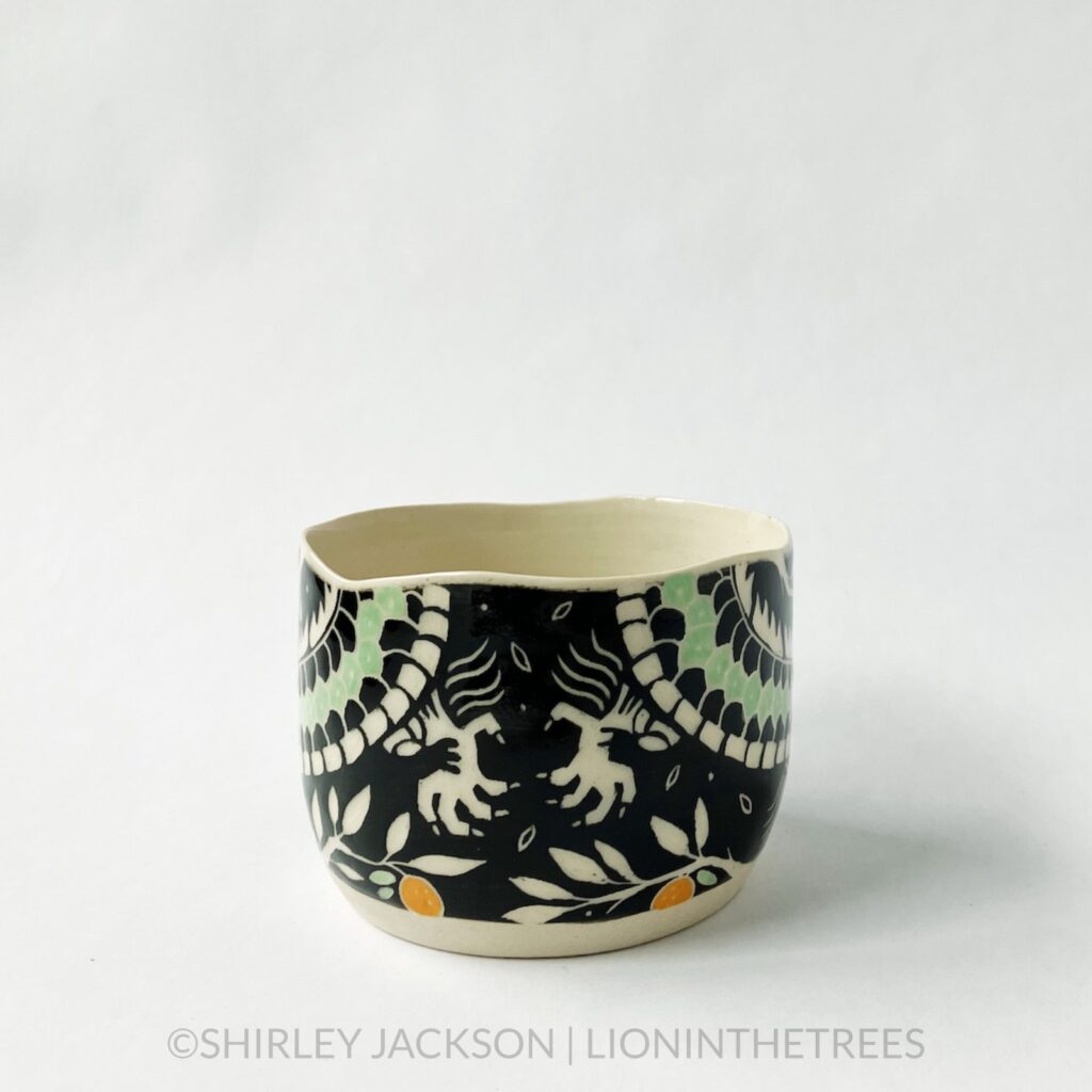 Dragon bowl featuring twins of my sgraffito dragon motif. This one was done with black and pistachio green underglaze, tree branches, and oranges. This photo shows the back of the bowl as the two dragon bodies meet and appear as though they are about to hold hands.