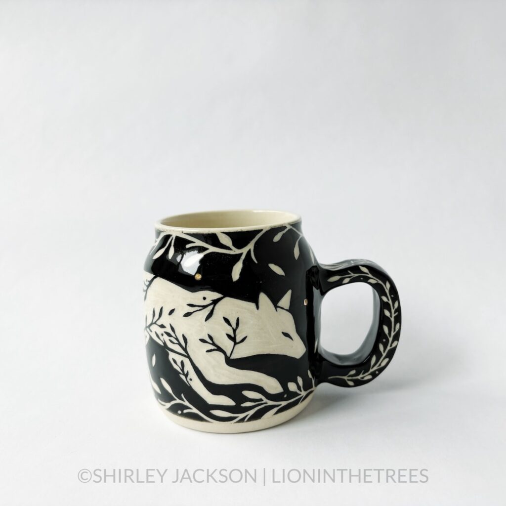 Ceramic black sgraffito mug featuring my Running Fox motif. This mug also features a floral border above and below the Fox motif.