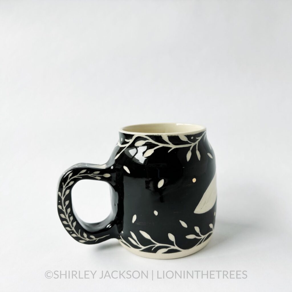 Ceramic black sgraffito mug featuring my Running Fox motif. This mug also features a floral border above and below the Fox motif.