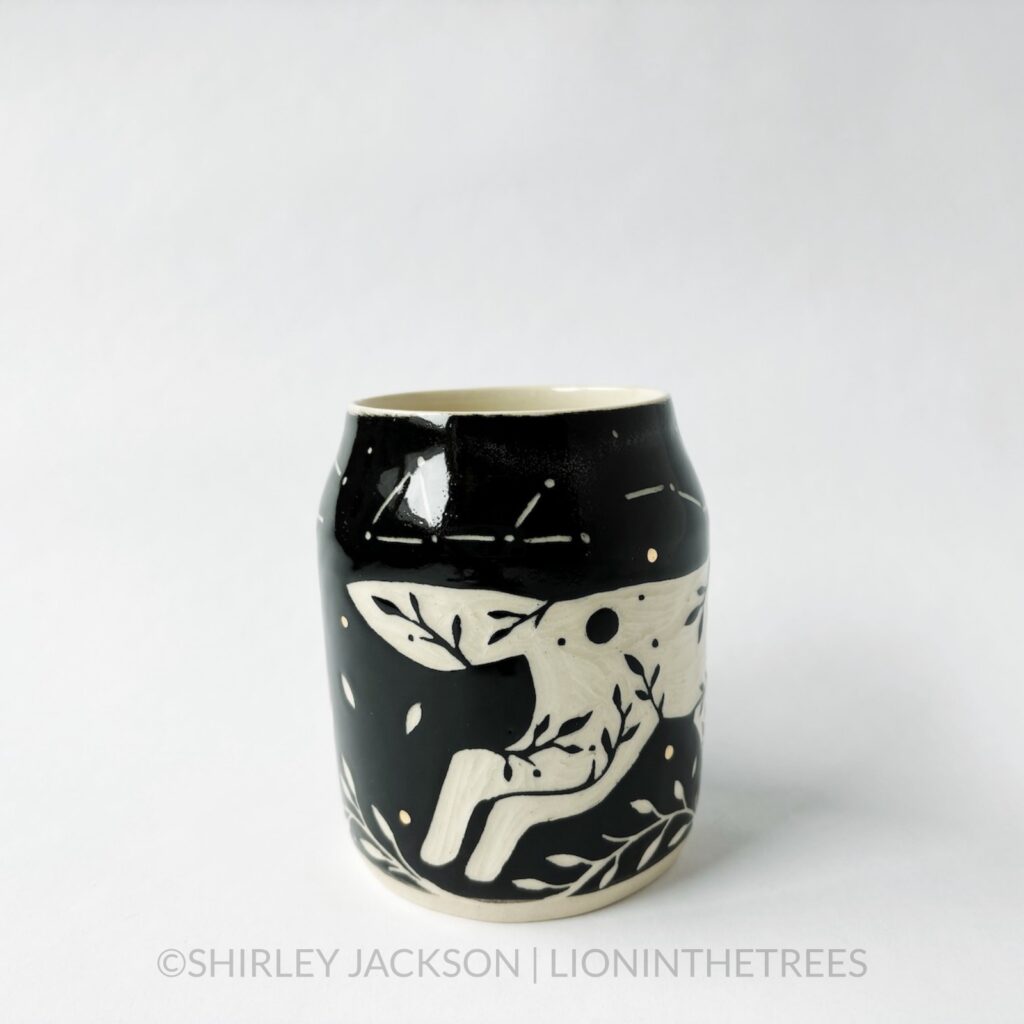 Ceramic black sgraffito mug featuring my Running Wolf motif. This mug also features a floral border above and below the Wolf motif.