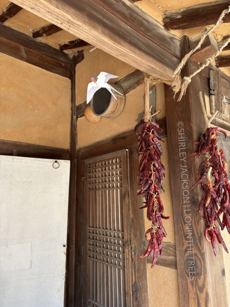 Photo of a paper barn swallow with dried red peppers hanging from a ceiling of a folk village home