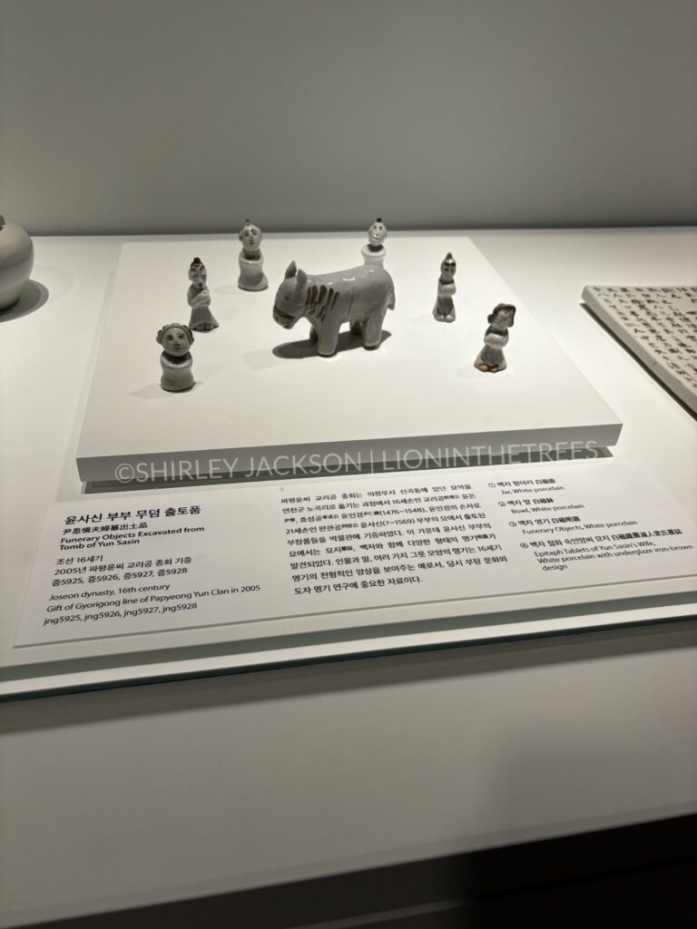 Photo of funerary objects excavated from the Tomb of Yun Sasin. They are very small sculptures of people and what appears to be a horse or cow.