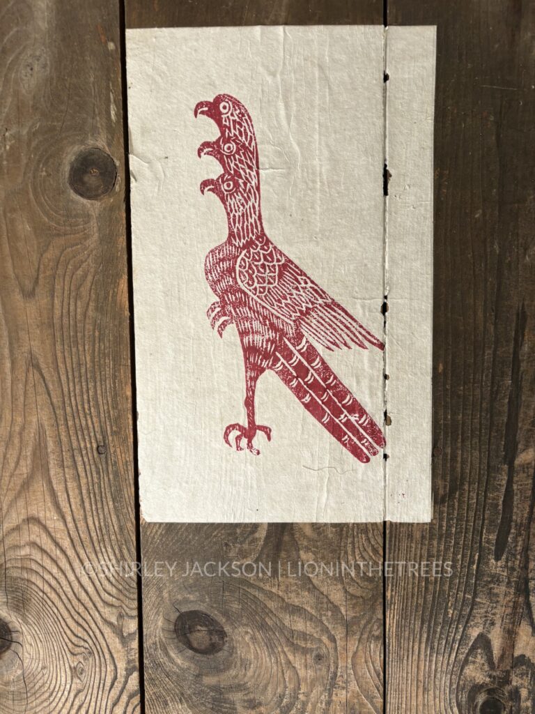 Photo of a woodblock print of the three headed hawk with one foot.