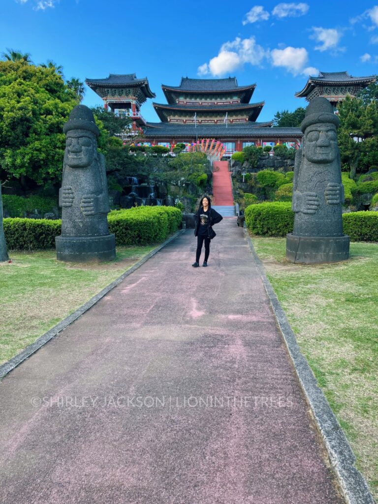 Photo of me standing in between two dol hareubang statues with the Buddha temple behind me