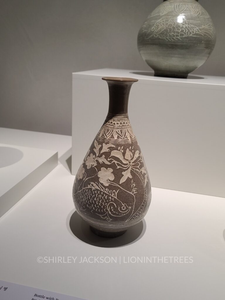 Photo of a brown vase with a fish that appears to have been sgraffito