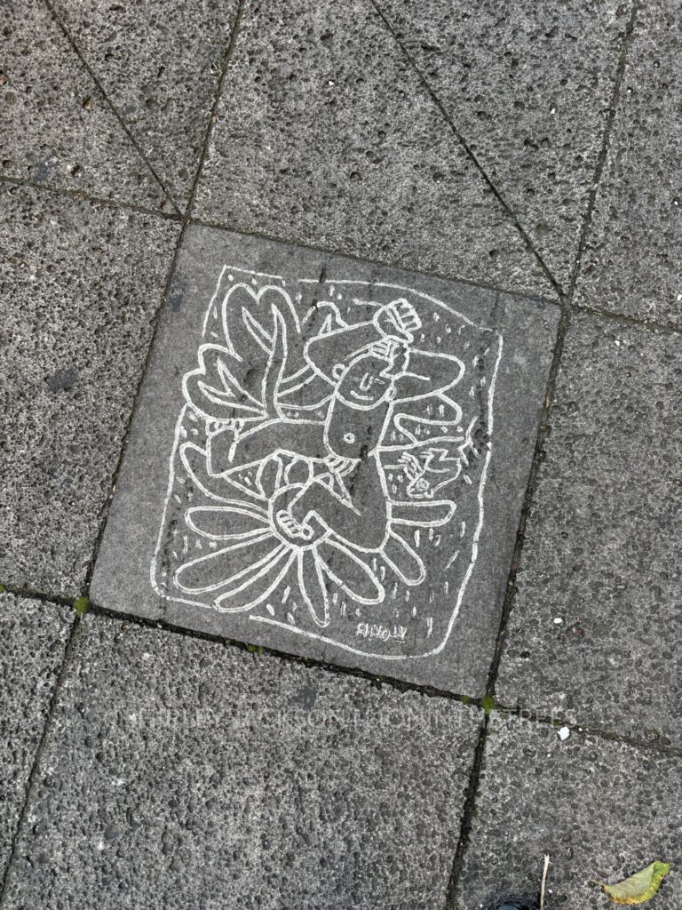 art found on the sidewalk of jeju island portraying a nude man dancing on top of flowers