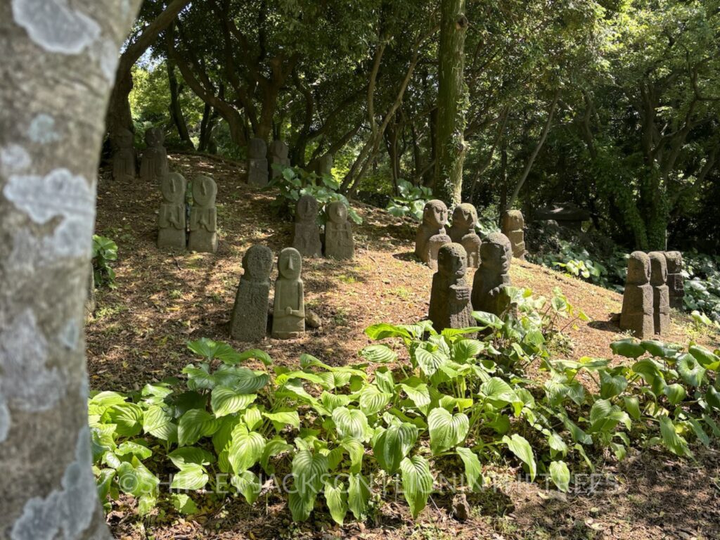 Photo of a group of small human shaped rock statues displayed on a hill.