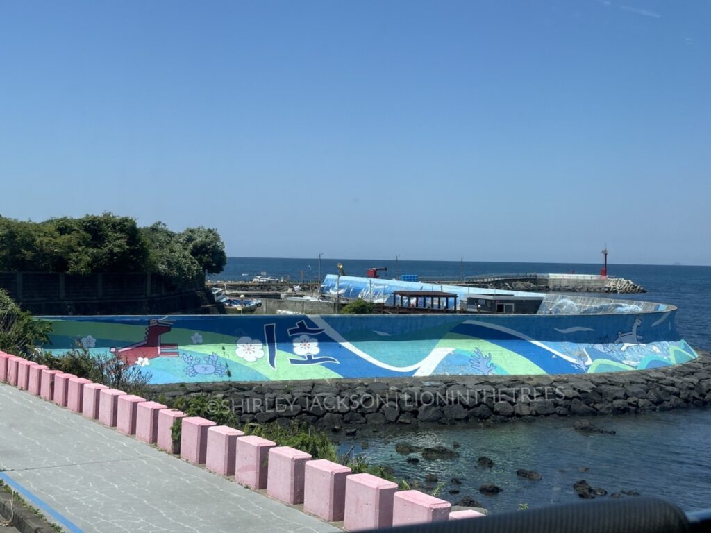 A photo of a mural along a part of the coast of Jeju Island featuring their horse lighthouses frolicking.