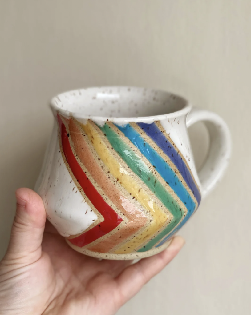 Gloss white mug with rainbow stripes on a white speckled clay body. Made by Nissa Arts