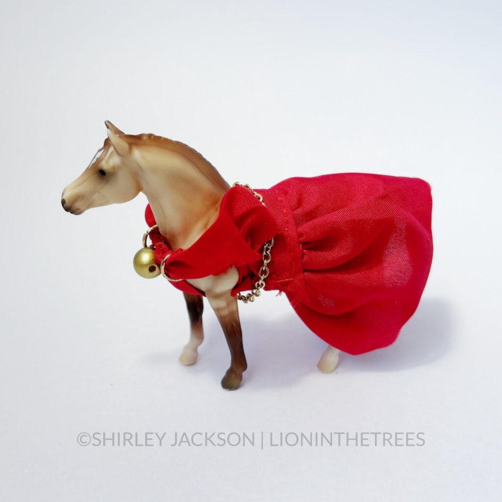 A dun mare dressed in a red mare with a gold belt