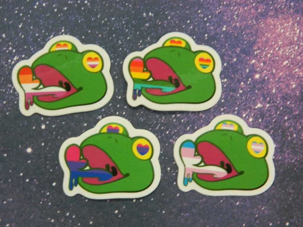 A set of gay frog stickers where they each symbolise different LGBTQ+ flags. Made by Averted Visionary.