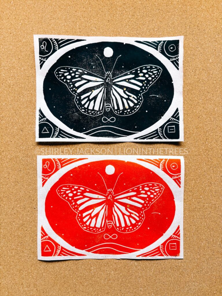 Photo of two relief prints featuring a monarch butterfly with Leo astrological symbols and associations within the design. One is done with black ink and the other is done in red to symbolise Leo's connection to the element of fire.