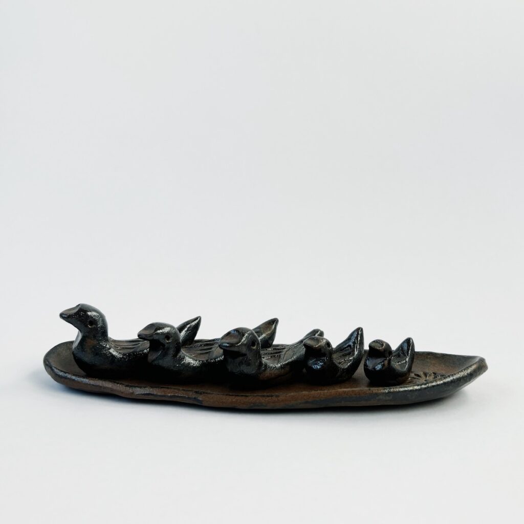 A family of onggi ceramic ducks resting on a leaf shaped plate.