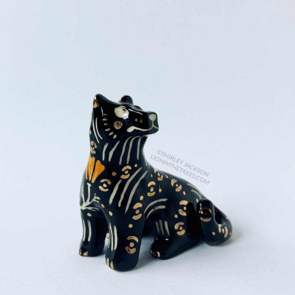 Right front view of the Black Panther totem. This piece was done with orange and black underglaze, gold overglaze, and a clear glaze.