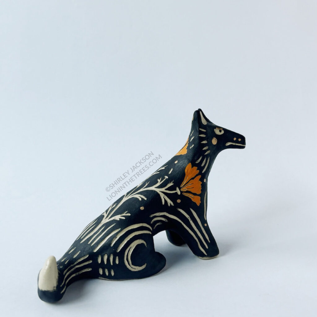 Right side view of the sitting wolf totem showing the gold overglaze details and crescent moon carved into it's back leg