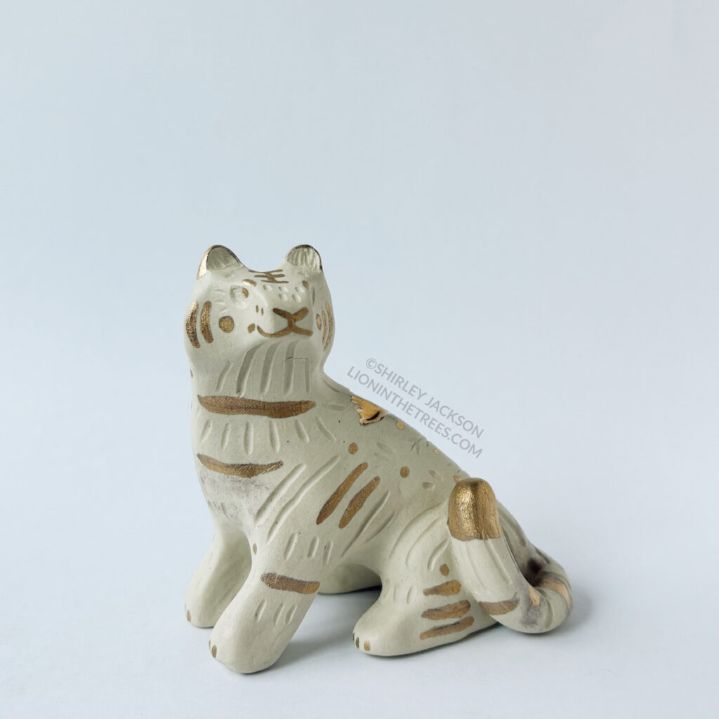 Front view of the White tiger totem done with no underglaze and gold overglaze in areas detailing the stripes and facial details of the tiger.