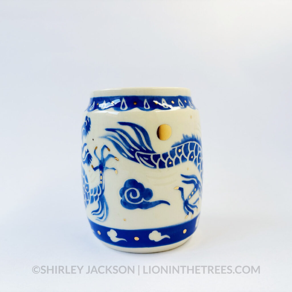 Large sgraffito vessel done with blue underglaze featuring a dragon motif that curls around the entire vessel. There are also gold overglaze details throughout the piece.