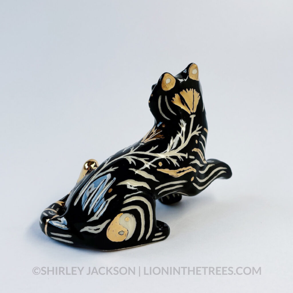 Back side view. Sgraffito Black Tiger totem done with black underglaze and gold overglaze for some of the stripe details. The back shows the yin-yang design on the back leg as well as the California Poppy motif crawling up the back of the tiger.