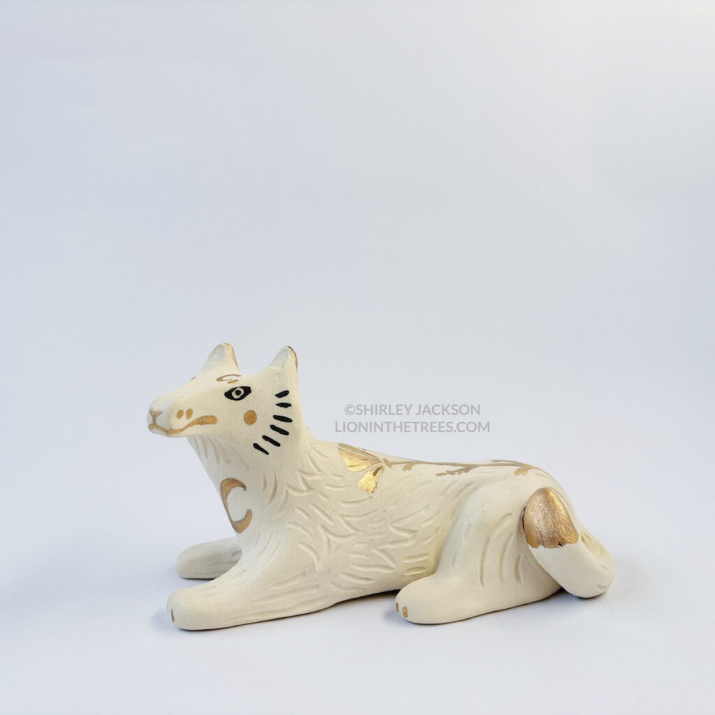 Left view of a sgraffito white wolf ceramic sculpture with gold overglaze details such as crescent moons, and my signature California Poppy motif on the top of it's body.