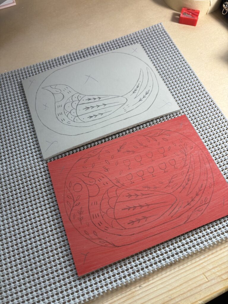 Photo of the two linoleum blocks before carving. One is painted with an acrylic wash done in red.