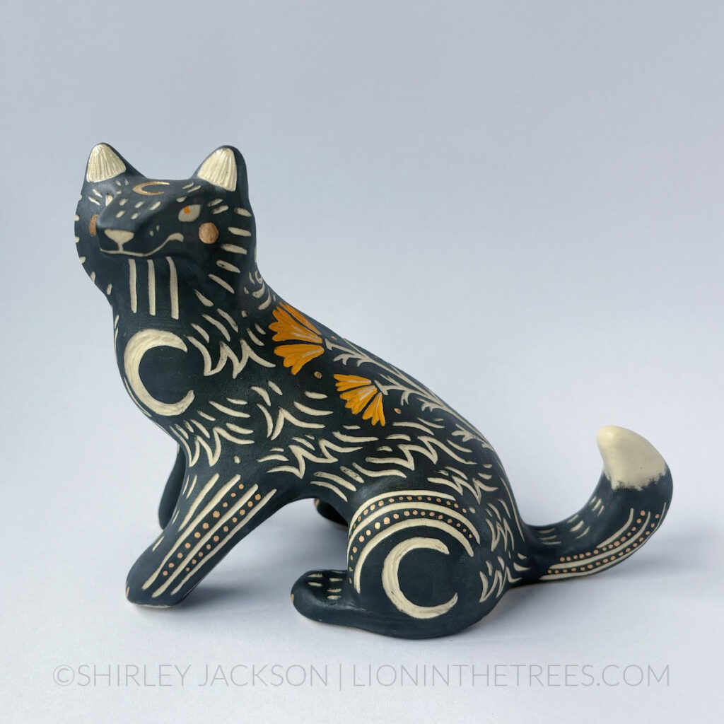 Black underglaze sgraffito wolf with California Poppies and crescent moon details all over it's body.