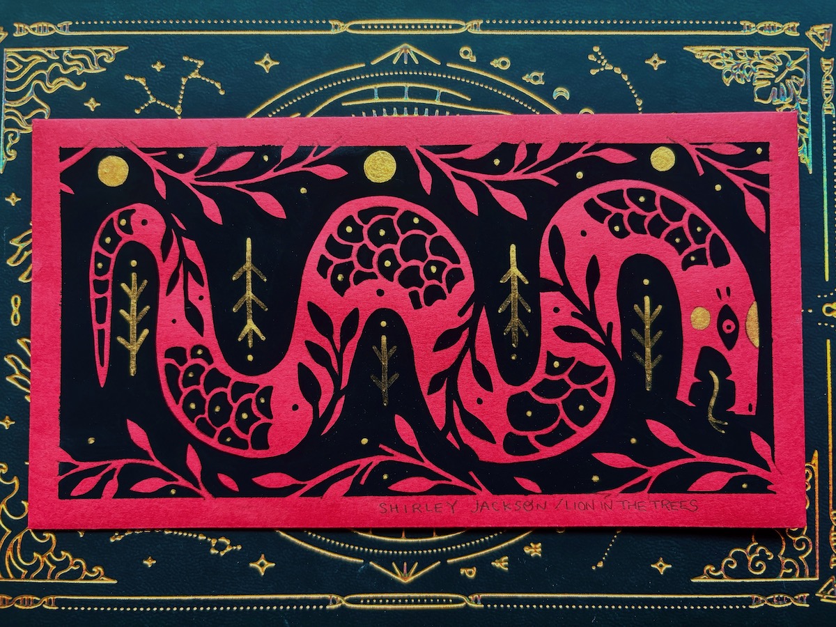 A horizontal painting done with black and gold paint on a red envelope used during Lunar New Year celebrations. The painting features a snake with floral details surrounding it and blending into it’s body.