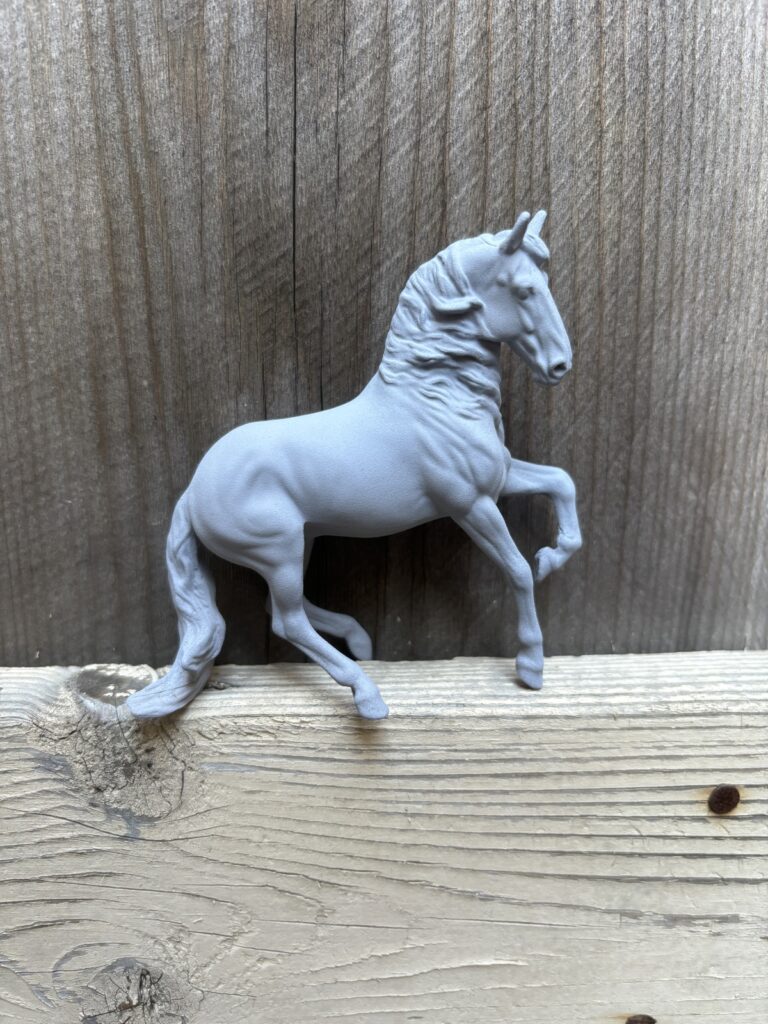 The model horse placed on top of a piece of wood coated in grey primer